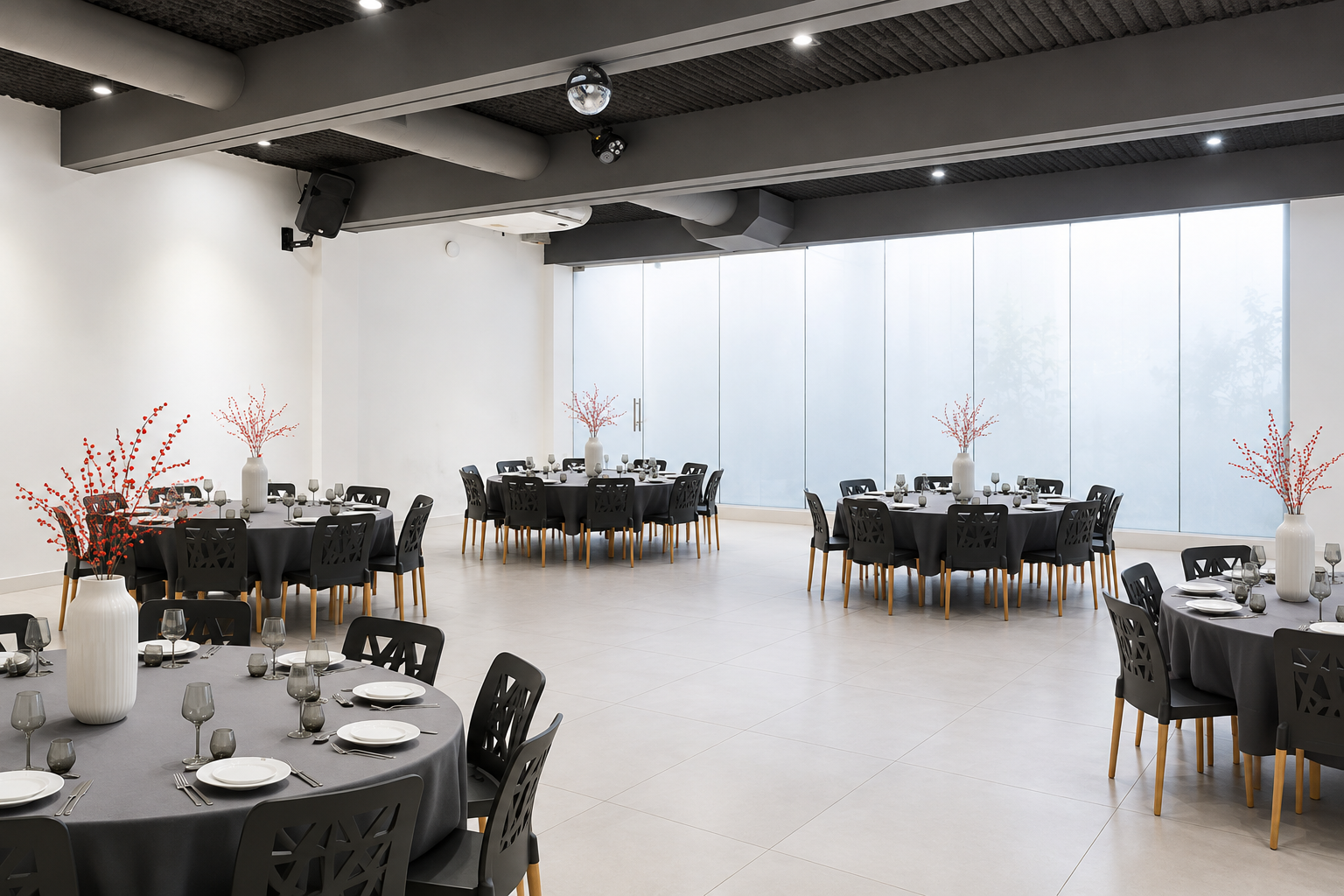 Salón de eventos con mesas vestidas de negro, grandes ventanales y una pista central.