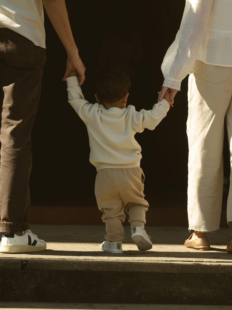 Toddler walking hand-in-hand with parents, symbolizing guidance, love, and raising children in a nurturing and faith-filled Christian home.
