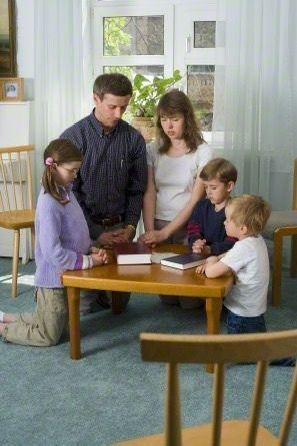 Christian family gathered around a table praying together with a Bible, demonstrating family devotion, unity, and growing closer to God at home. Christian family gathered around a table praying together with a Bible, demonstrating family devotion, unity, and growing closer to God at home.
