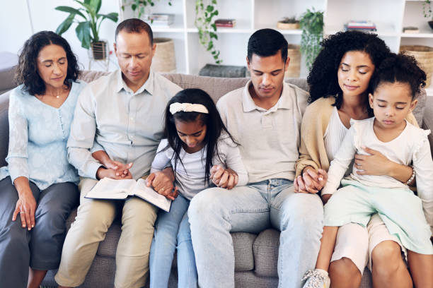Christian family sitting together on a couch holding hands in prayer, trusting God during difficult family seasons through faith, unity, and spiritual support. Christian family sitting together on a couch holding hands in prayer, trusting God during difficult family seasons through faith, unity, and spiritual support.