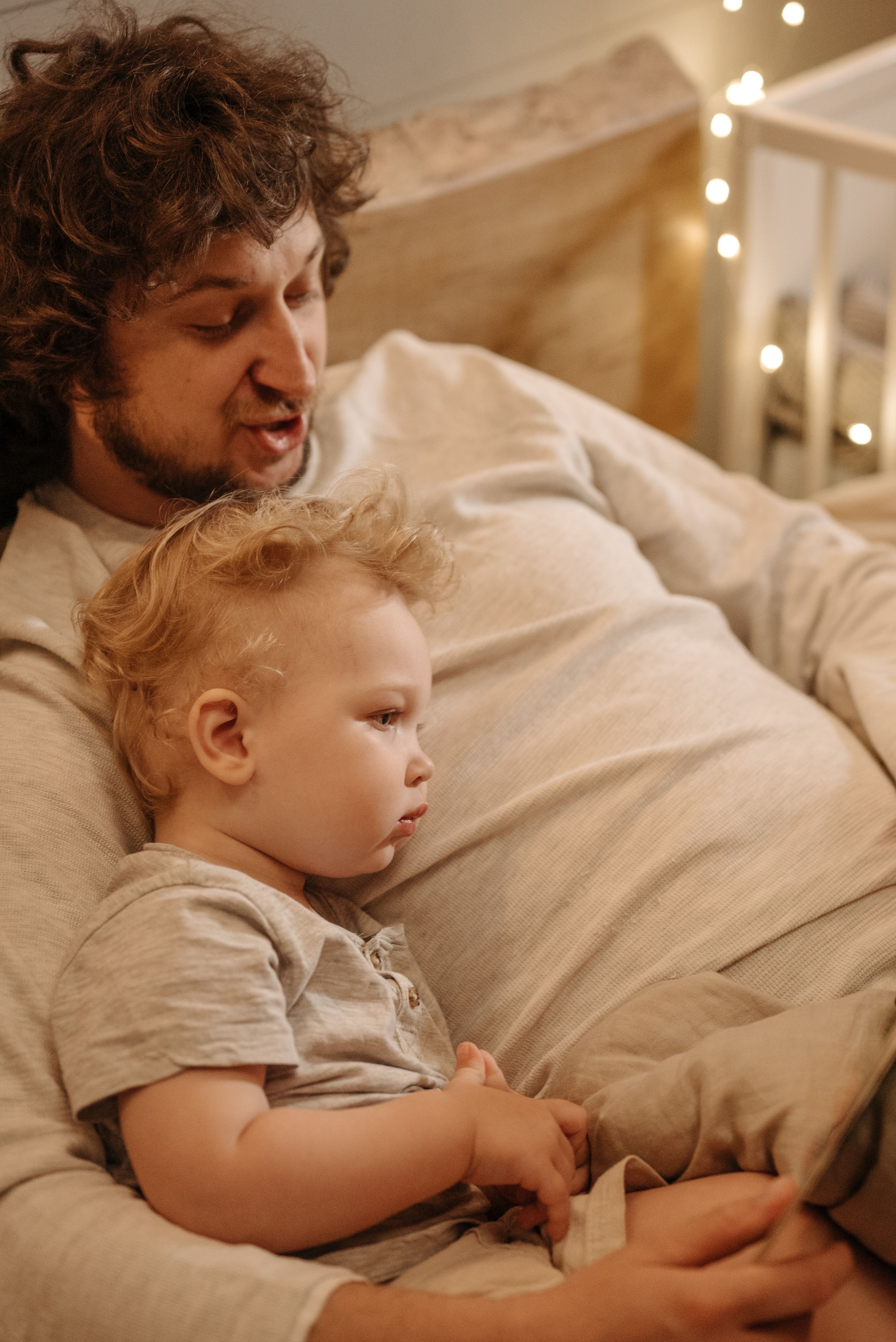 Father spending quiet quality time with his young child at home, sitting together on a bed and sharing a peaceful moment that reflects fatherly love, connection, care, and emotional support.