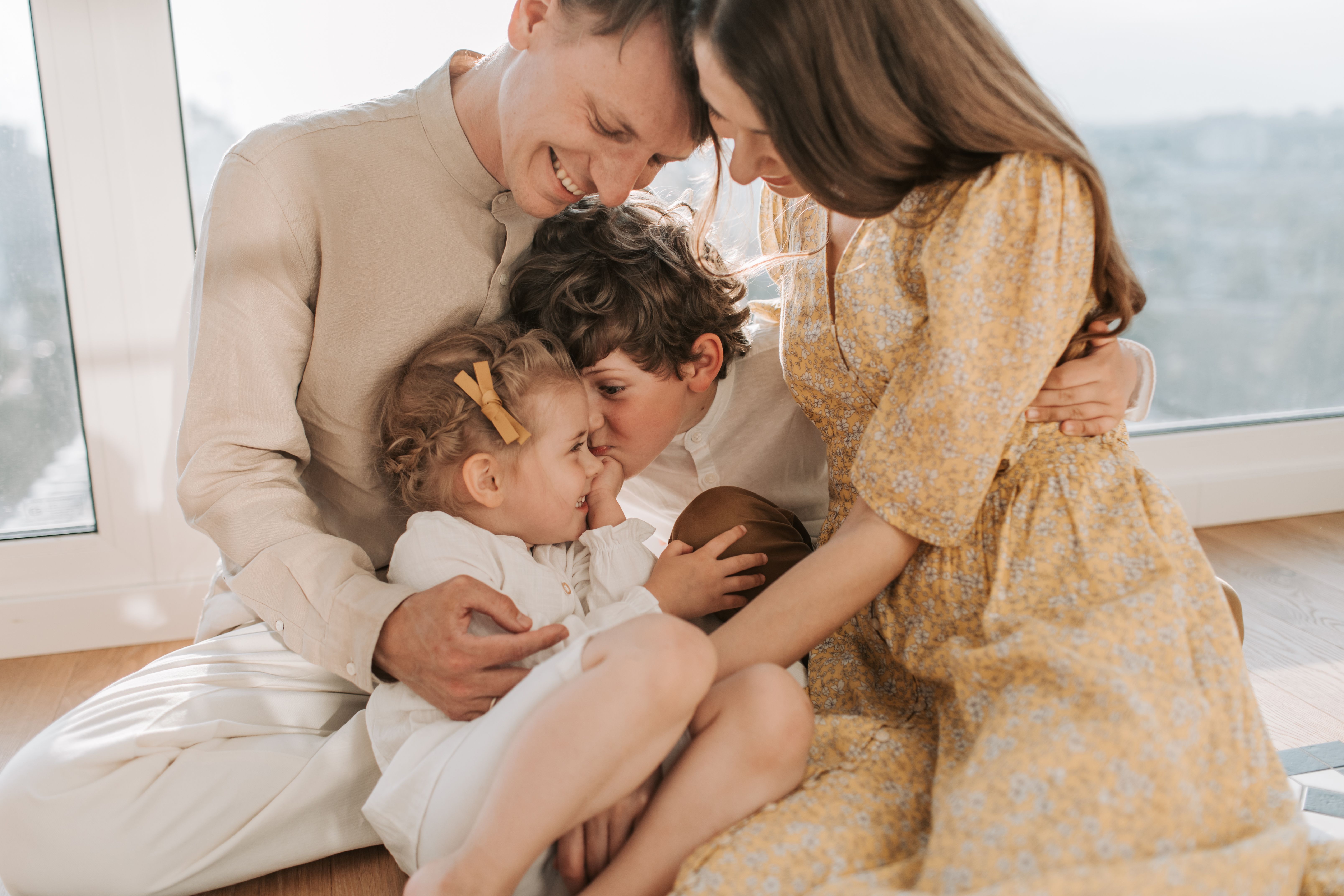 Loving family spending quality time together at home, parents embracing their children and creating a warm, supportive environment that promotes emotional safety, family connection, and belonging.