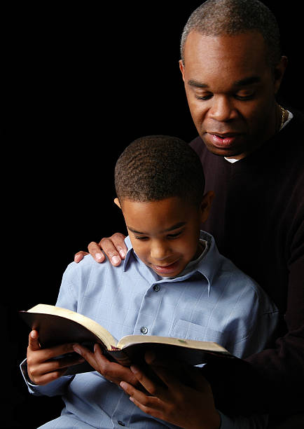 Christian father teaching his young son biblical manhood while reading the Bible together, showing faith, fatherhood, spiritual guidance, and the importance of raising boys with Christian values.