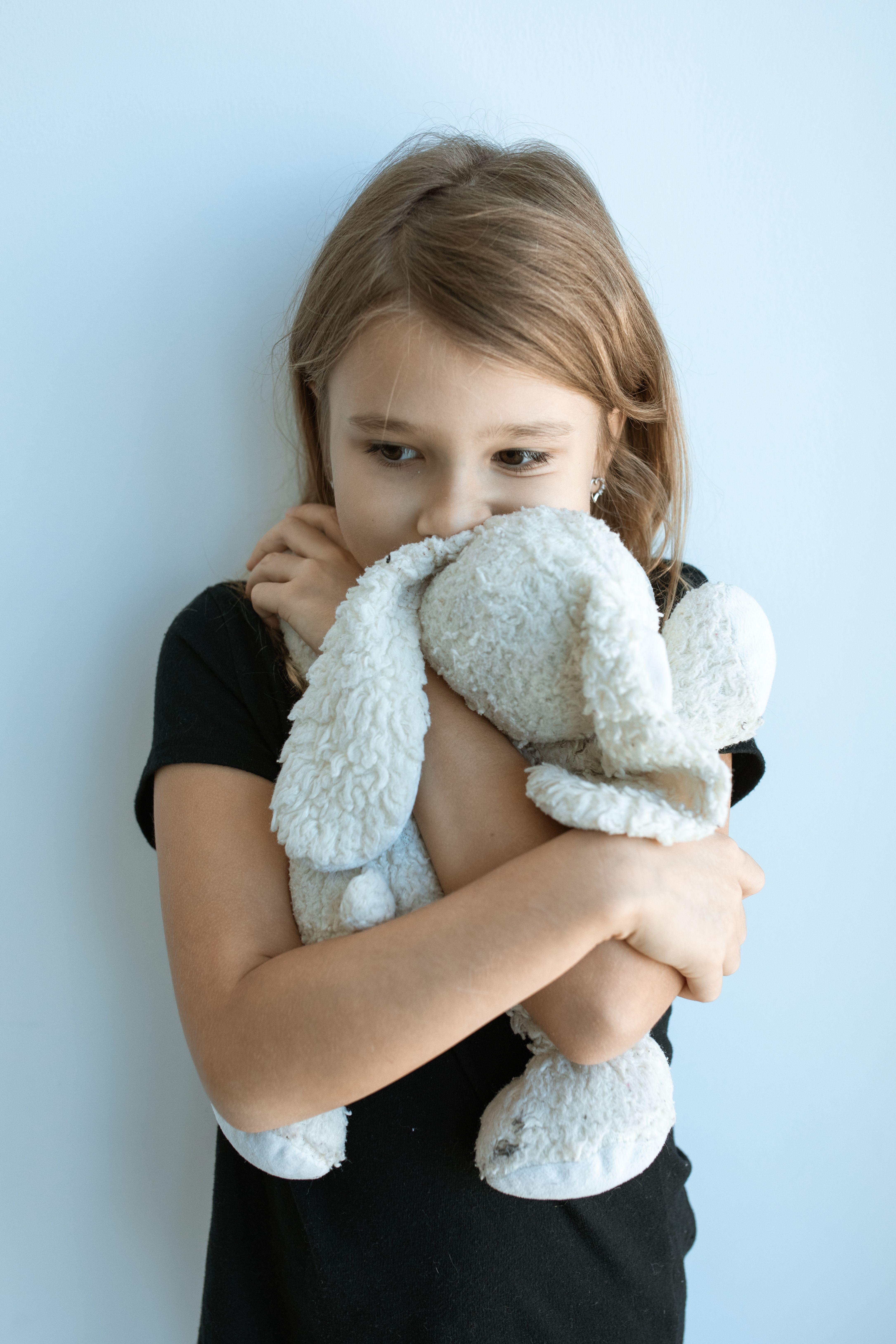 Young Girl Holding a White Stuffed Bunny for Comfort While Experiencing Fear and Anxiety, Illustrating Childhood Emotions and the Need for Parental Support.