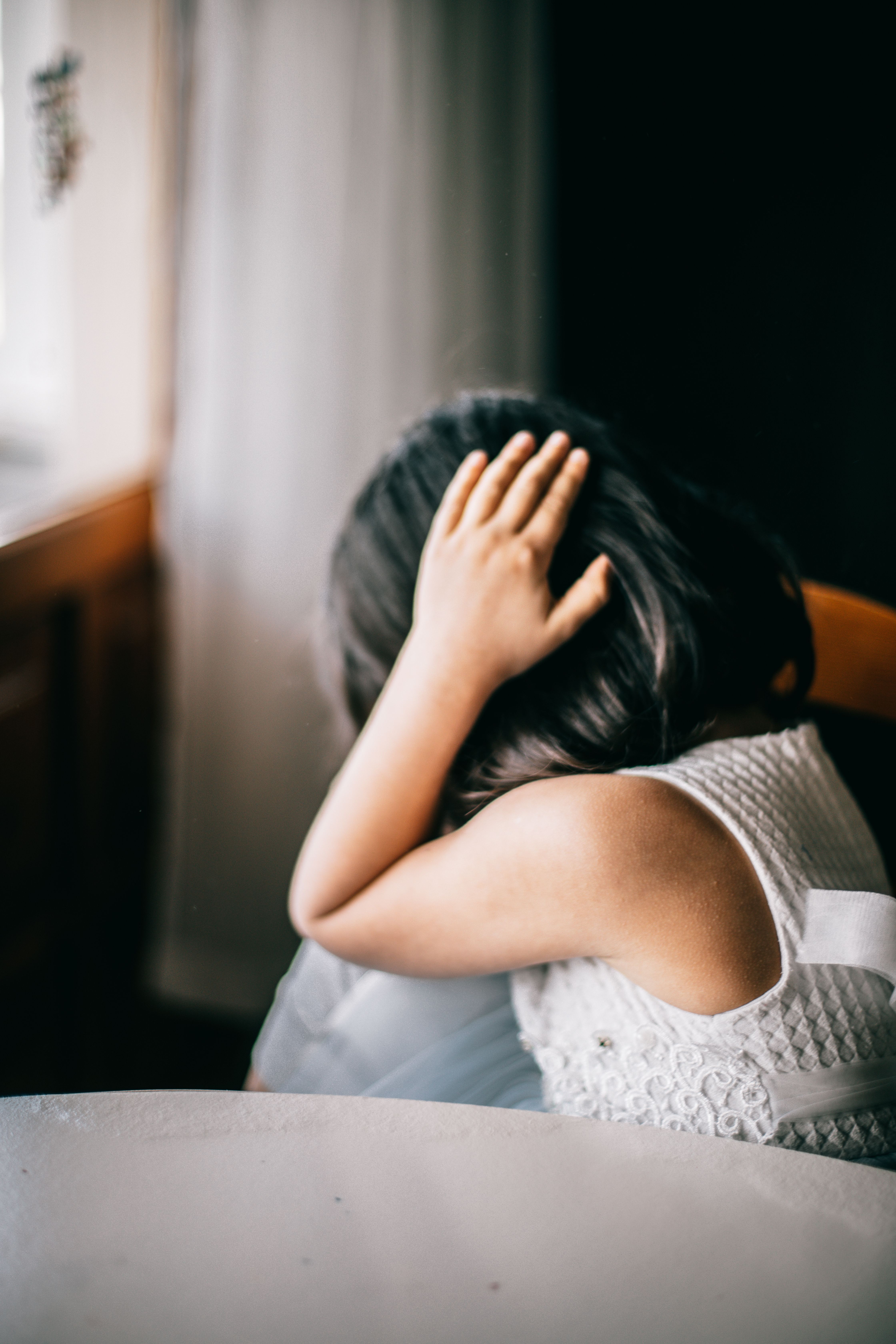 A young girl sitting alone with her head lowered and hand resting on her head, illustrating childhood emotional struggles and the need for parents to support quiet children with patience, understanding, and emotional care. A young girl sitting alone with her head lowered and hand resting on her head, illustrating childhood emotional struggles and the need for parents to support quiet children with patience, understanding, and emotional care.