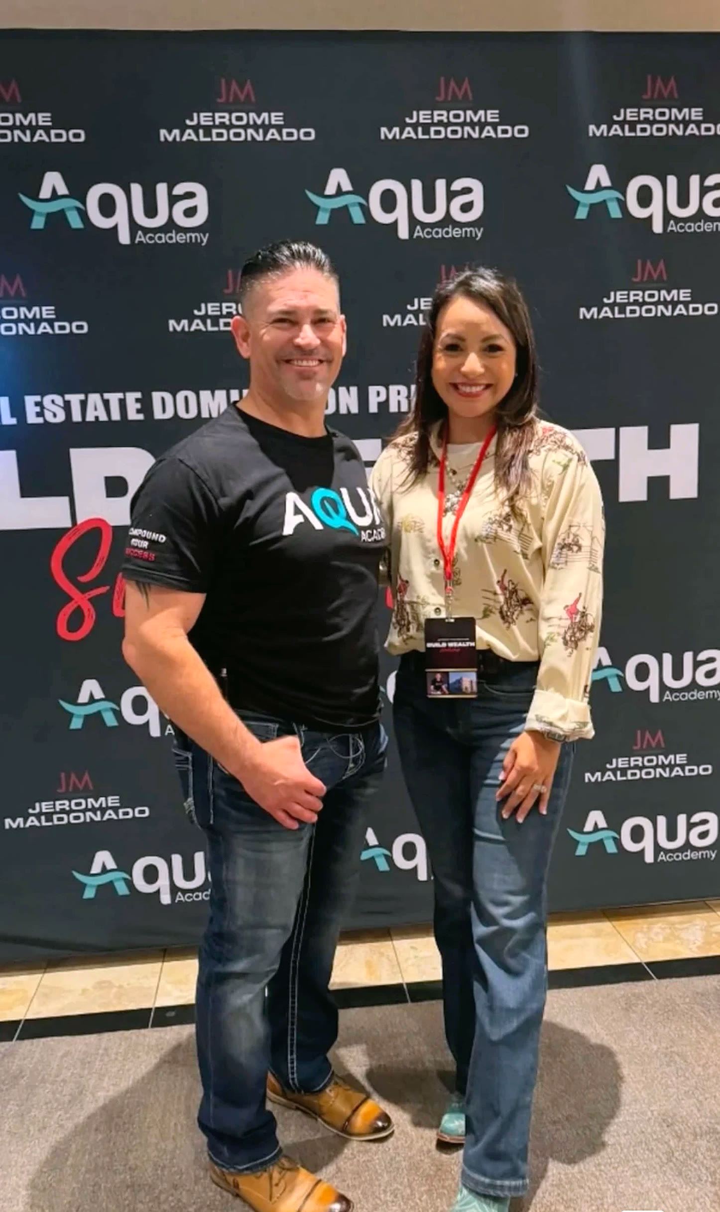 Two attendees at the Build Wealth Summit backdrop