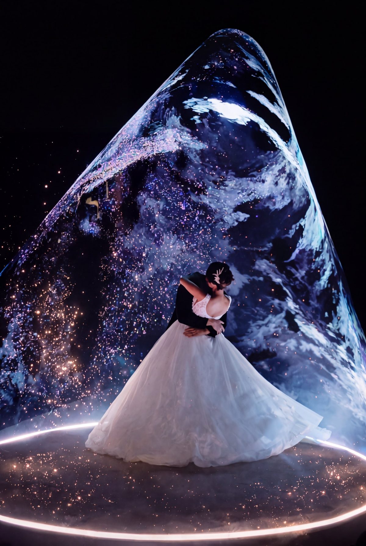 Los novios bailando dentro de un cono de luz sobre una plataforma iluminada, en una boda real