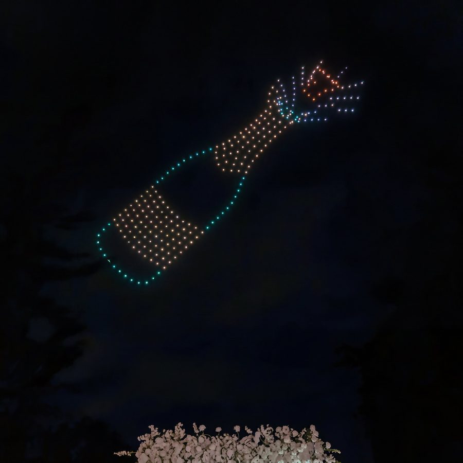 Drones drawing a champagne bottle in the night sky at a real wedding