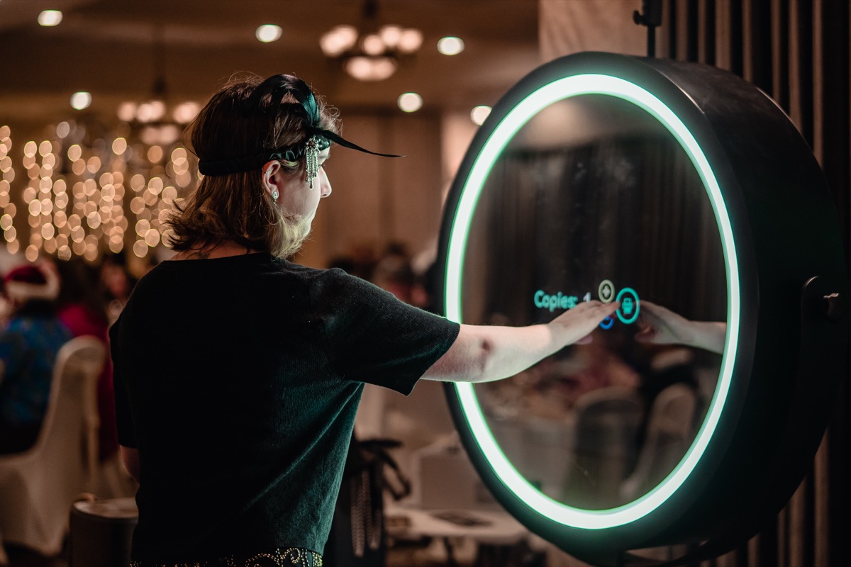 Guest tapping the glowing ring of the mirror photo booth at a reception