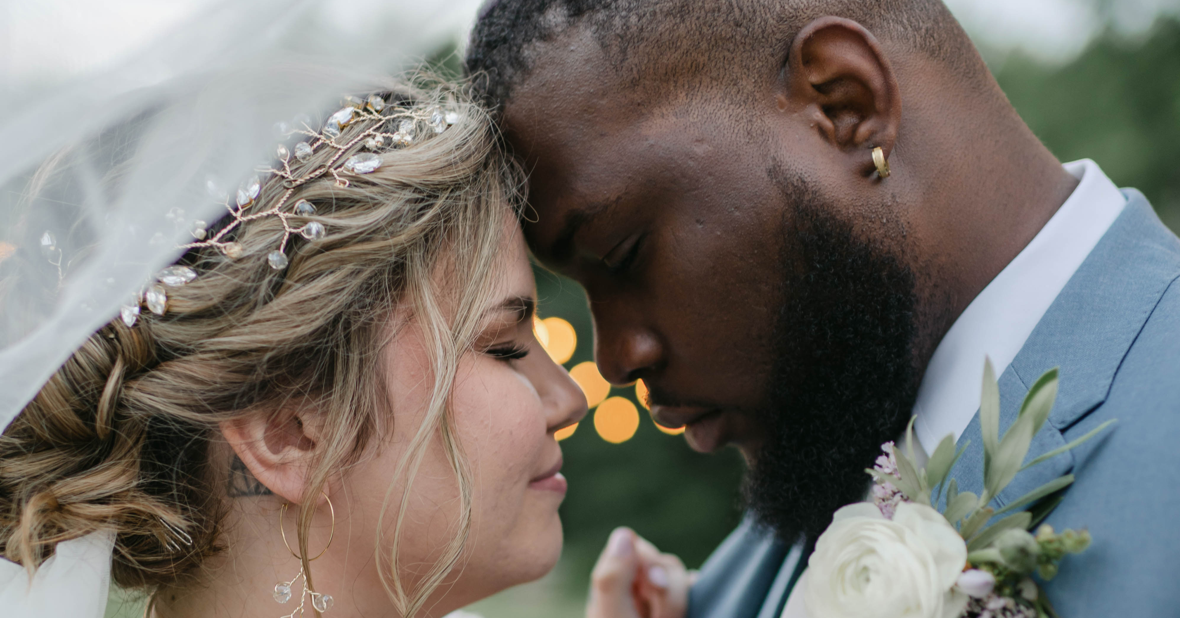 Bride and groom embrace at their Maine wedding, veil and boutonniere detail