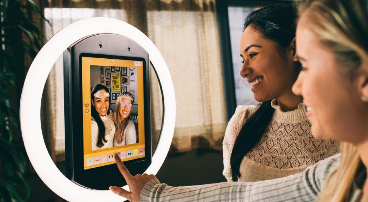 Two friends editing their photo on the selfie booth touchscreen
