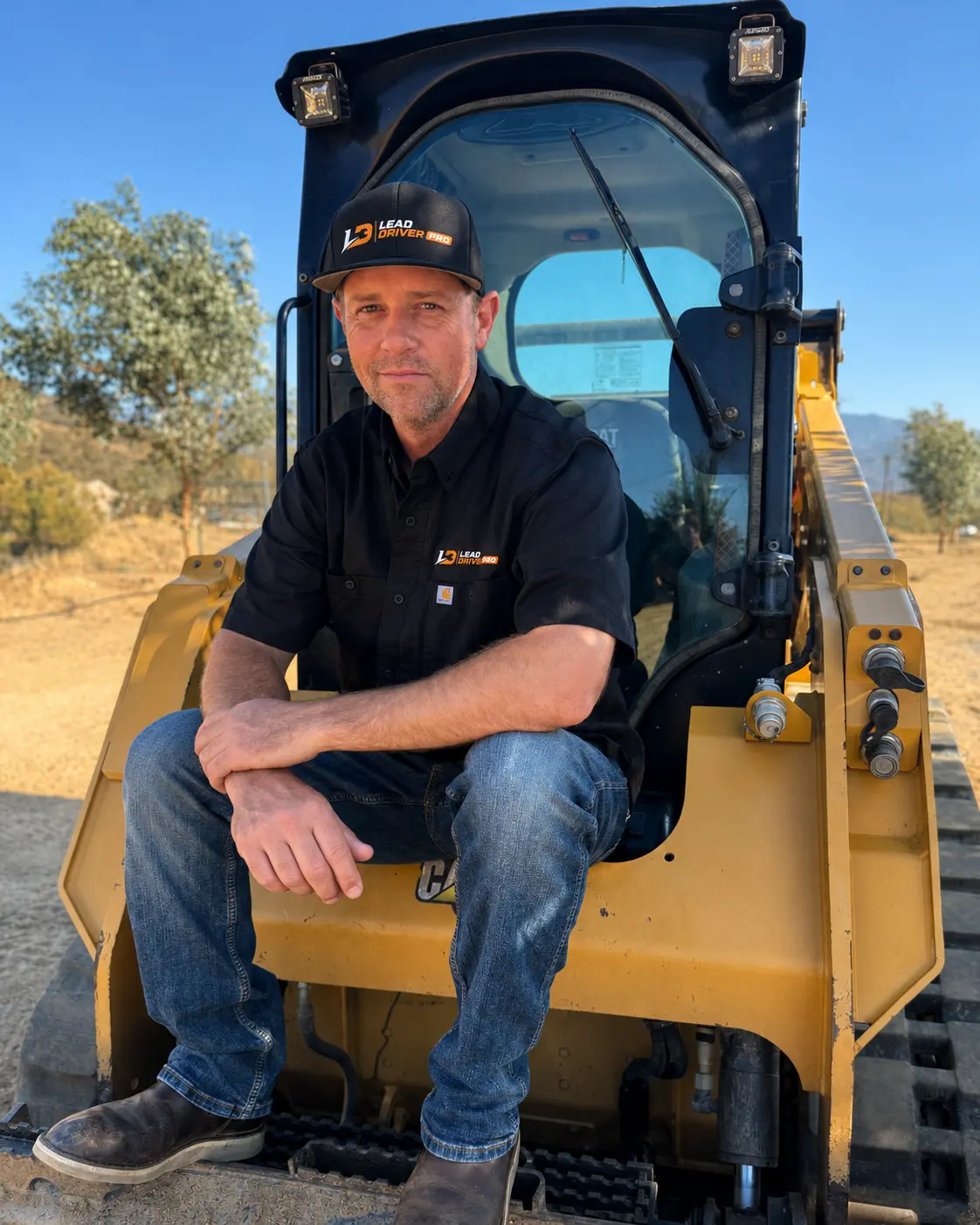 Brad Bokath, LeadDriverPRO co-founder, seated on a compact track loader at a job site in Integrity Optima work clothing