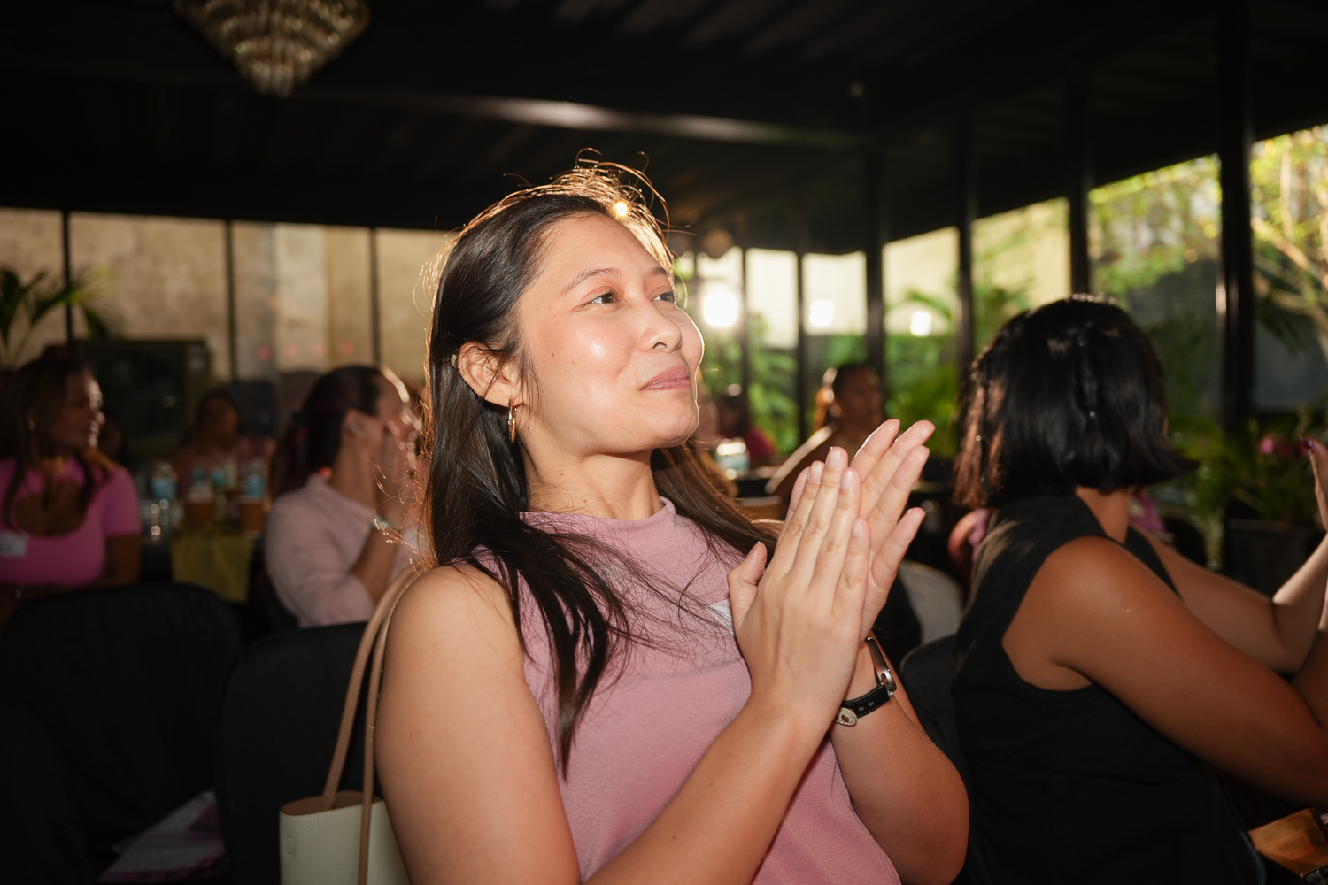 An attendee with her hands pressed together while listening