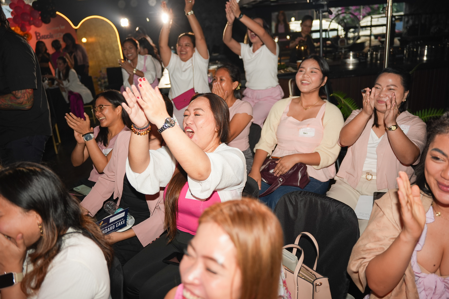 A row of attendees cheering with their hands in the air
