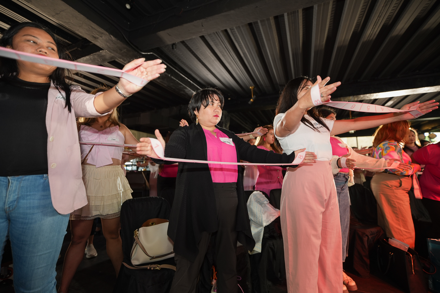 Attendees standing with their arms out holding a resistance band