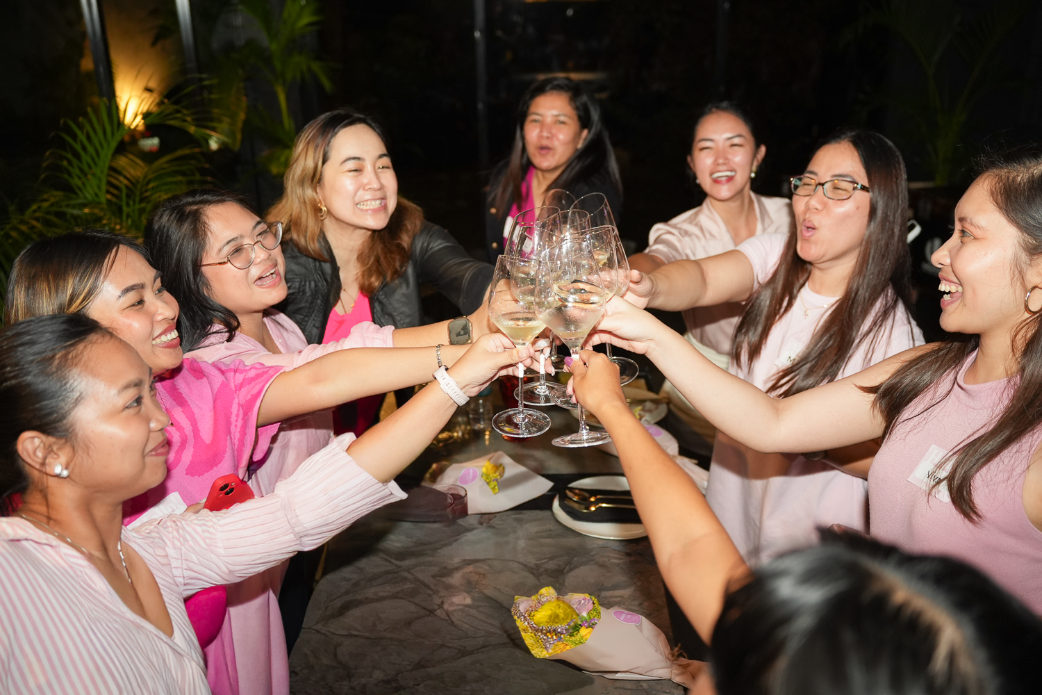 Attendees reaching in to clink glasses over the table