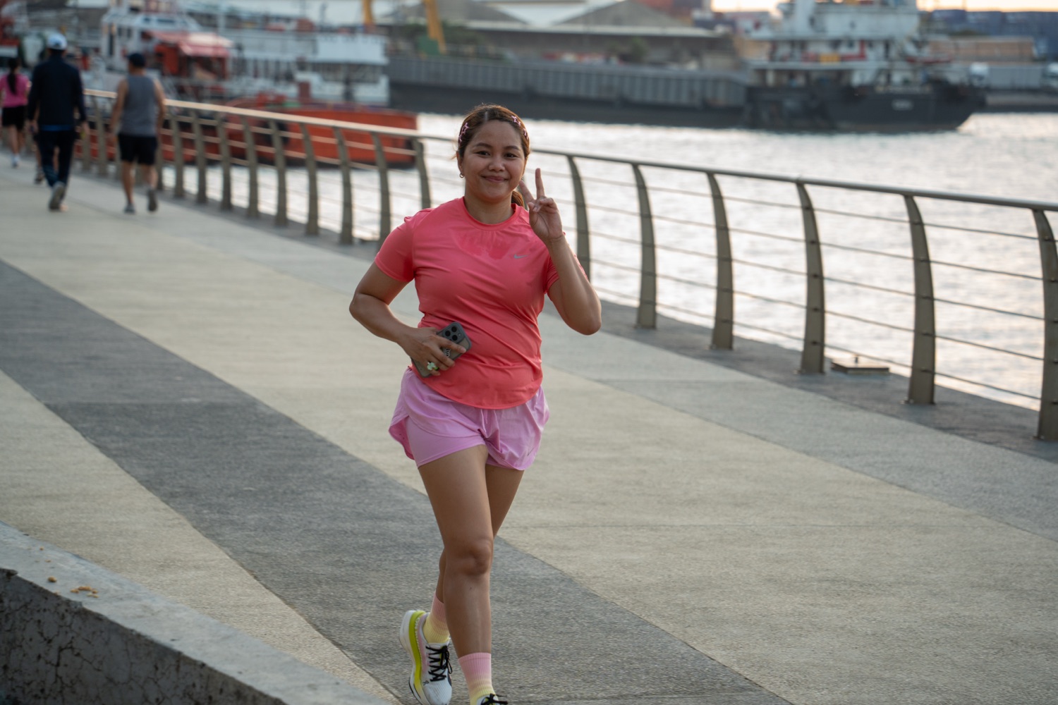 A member waving as she runs along the waterfront