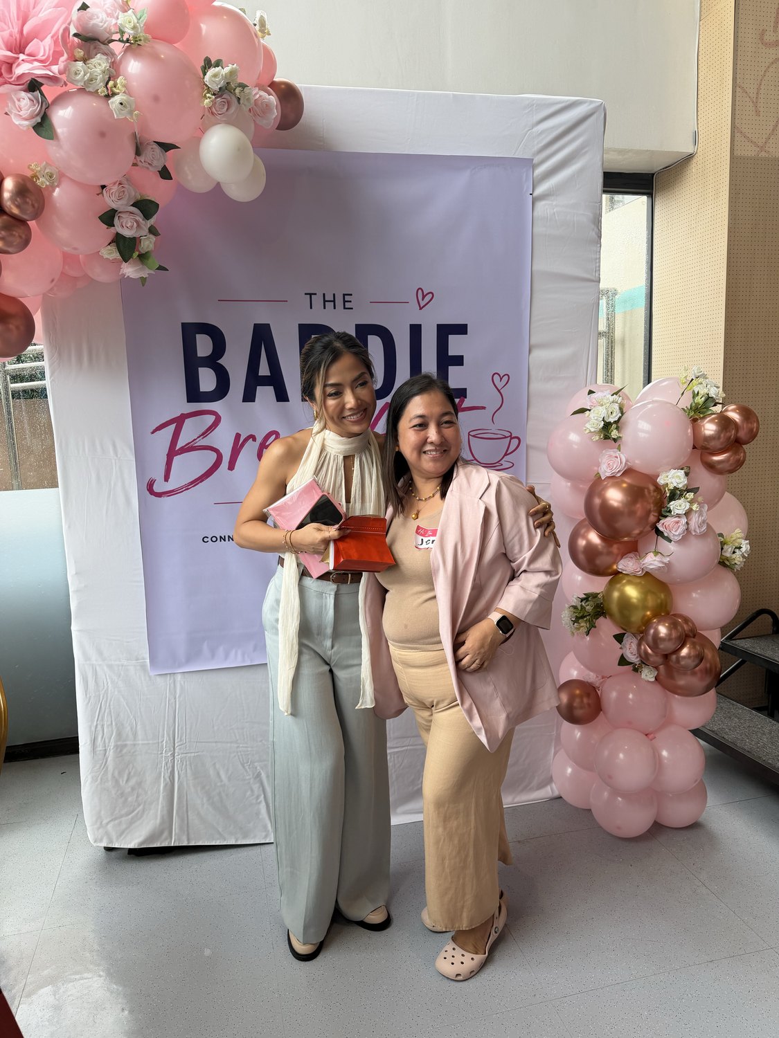 Two guests posing at the Baddie Breakfast Club backdrop