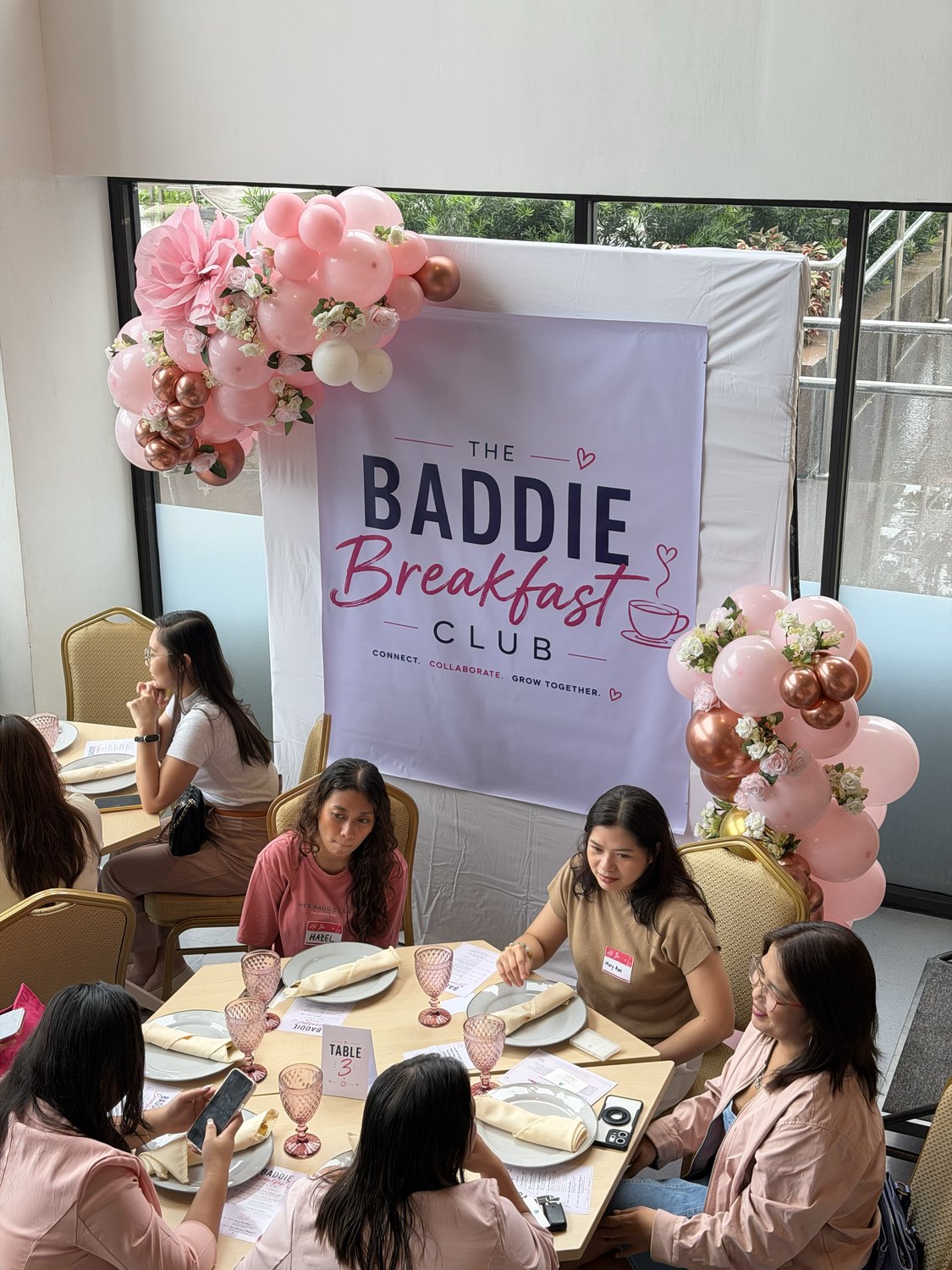 Guests at tables beside the balloon arch and club sign
