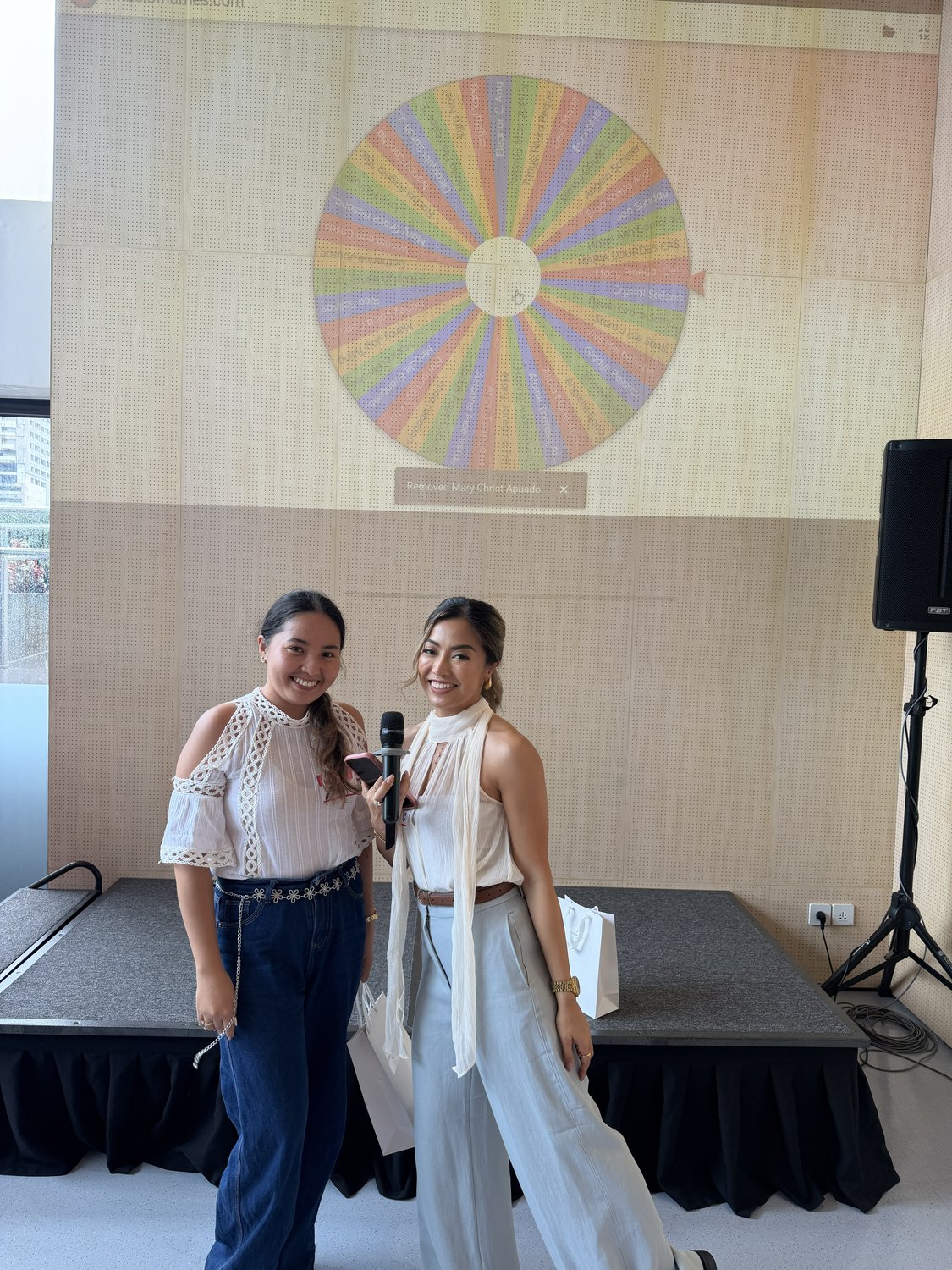 Two guests on stage beside the prize wheel