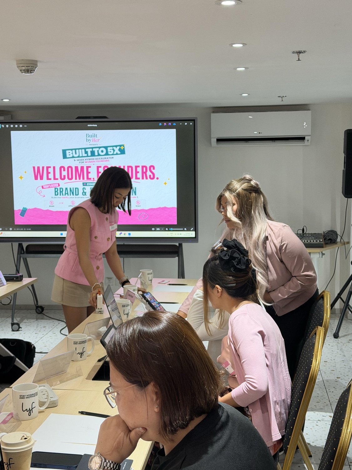 Facilitators helping founders at a laptop at Built to 5X