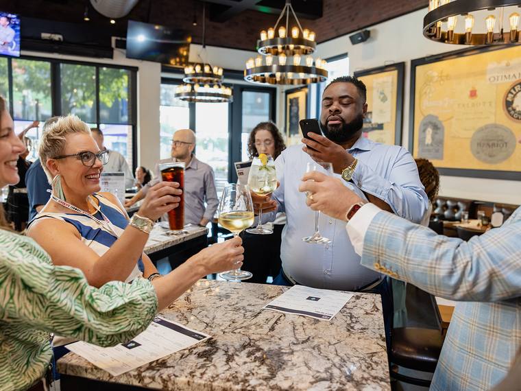 Four guests raising glasses together at a high-top during the cocktail hour.