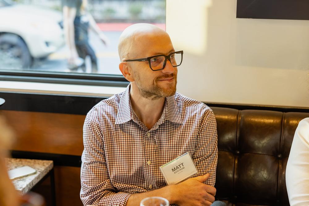 Matt Ekstrom seated at the table, listening to another guest.
