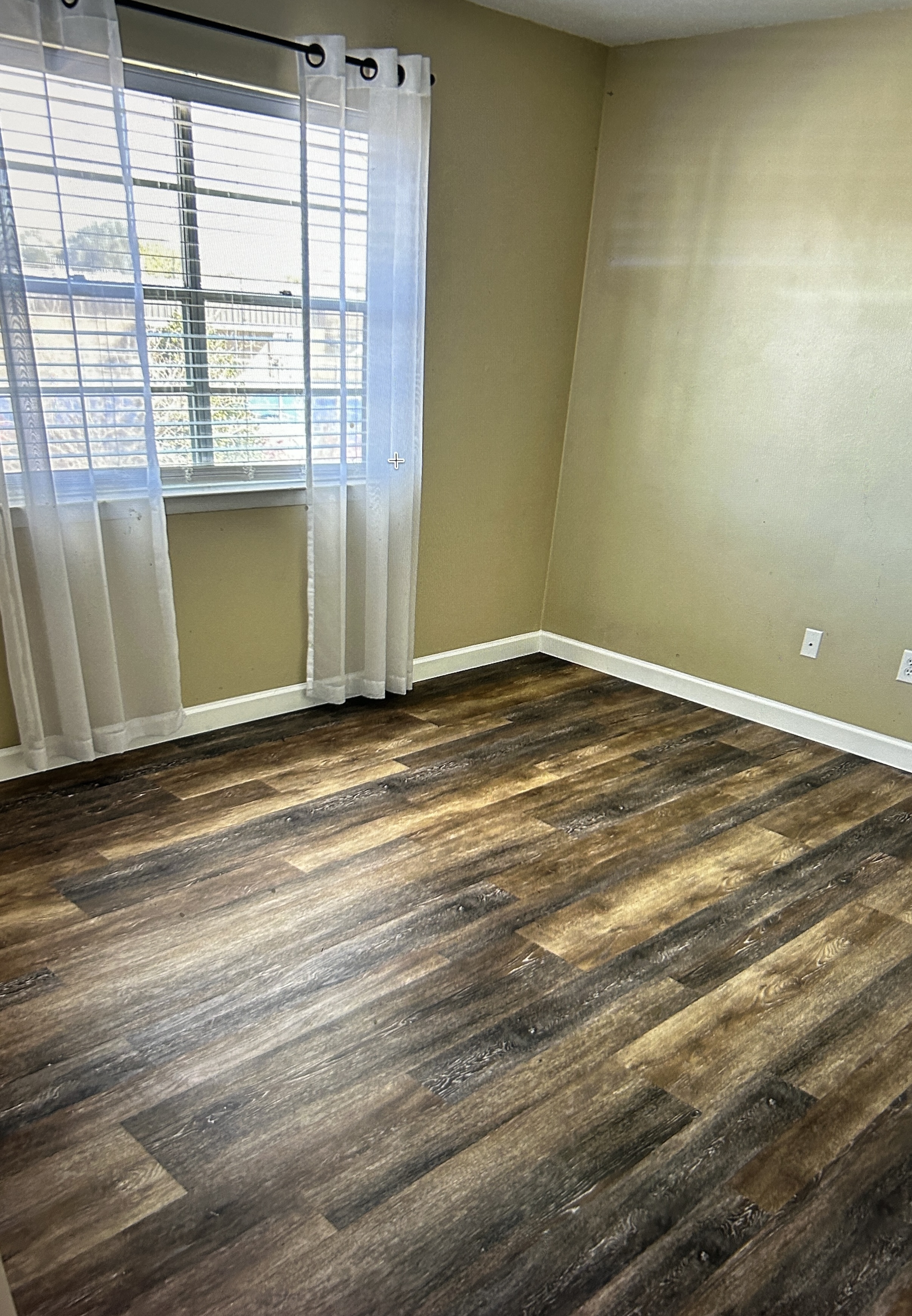 Bedroom corner with window and wood-style flooring
