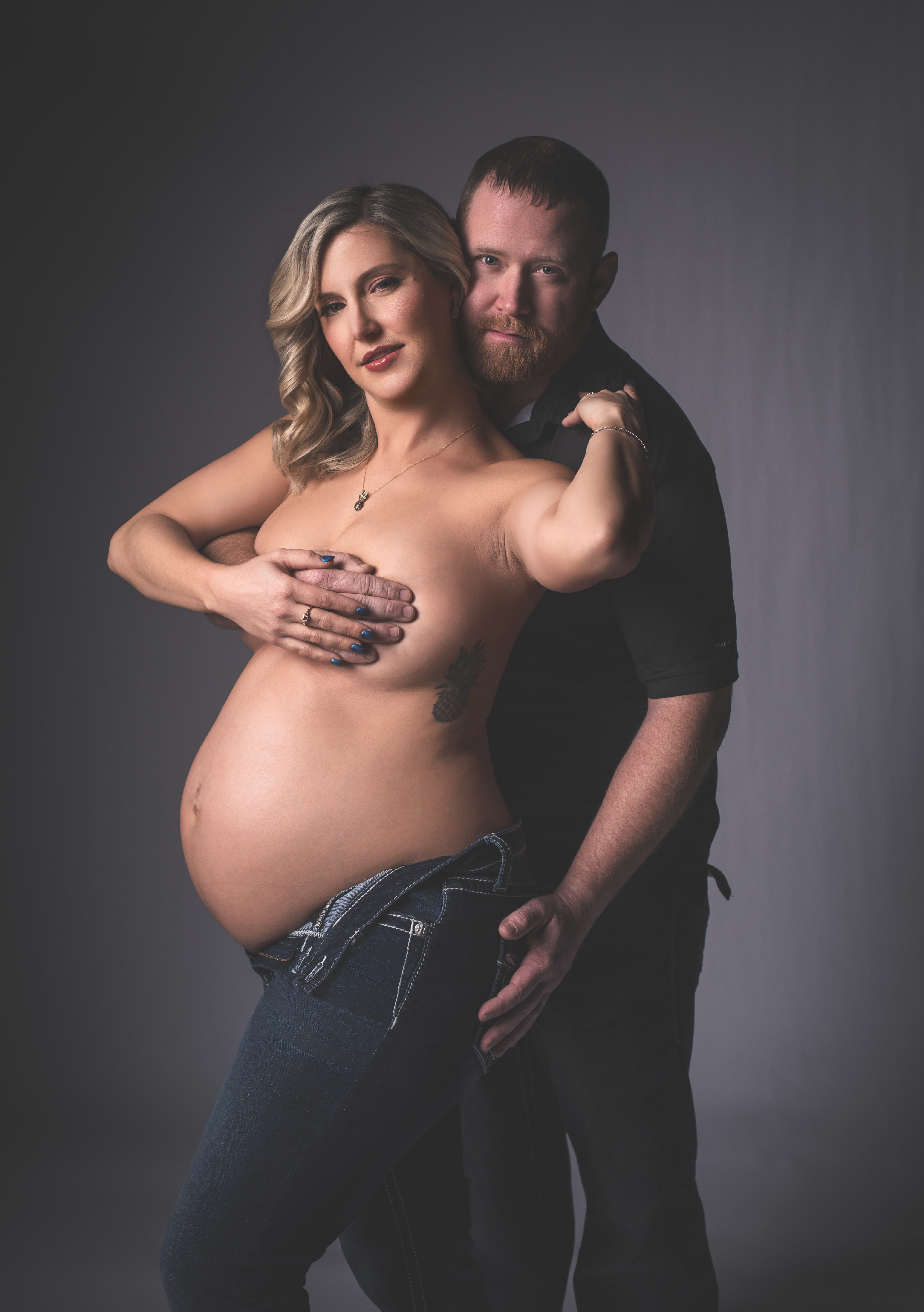 A side view of a pregnant mother wearing dark-wash over-the-belly maternity jeans paired 