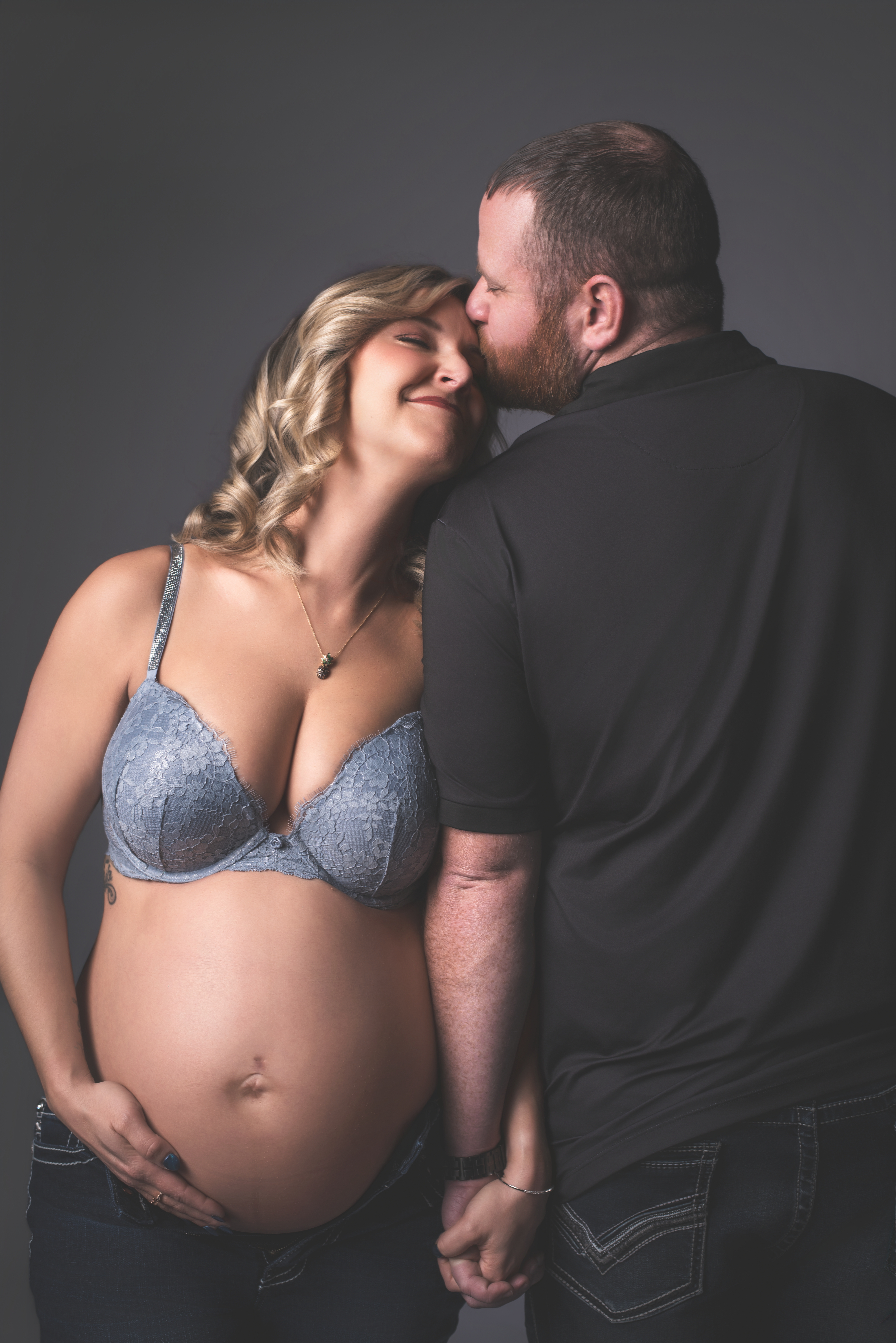 A side view of a pregnant mother wearing dark-wash over-the-belly maternity jeans paired 