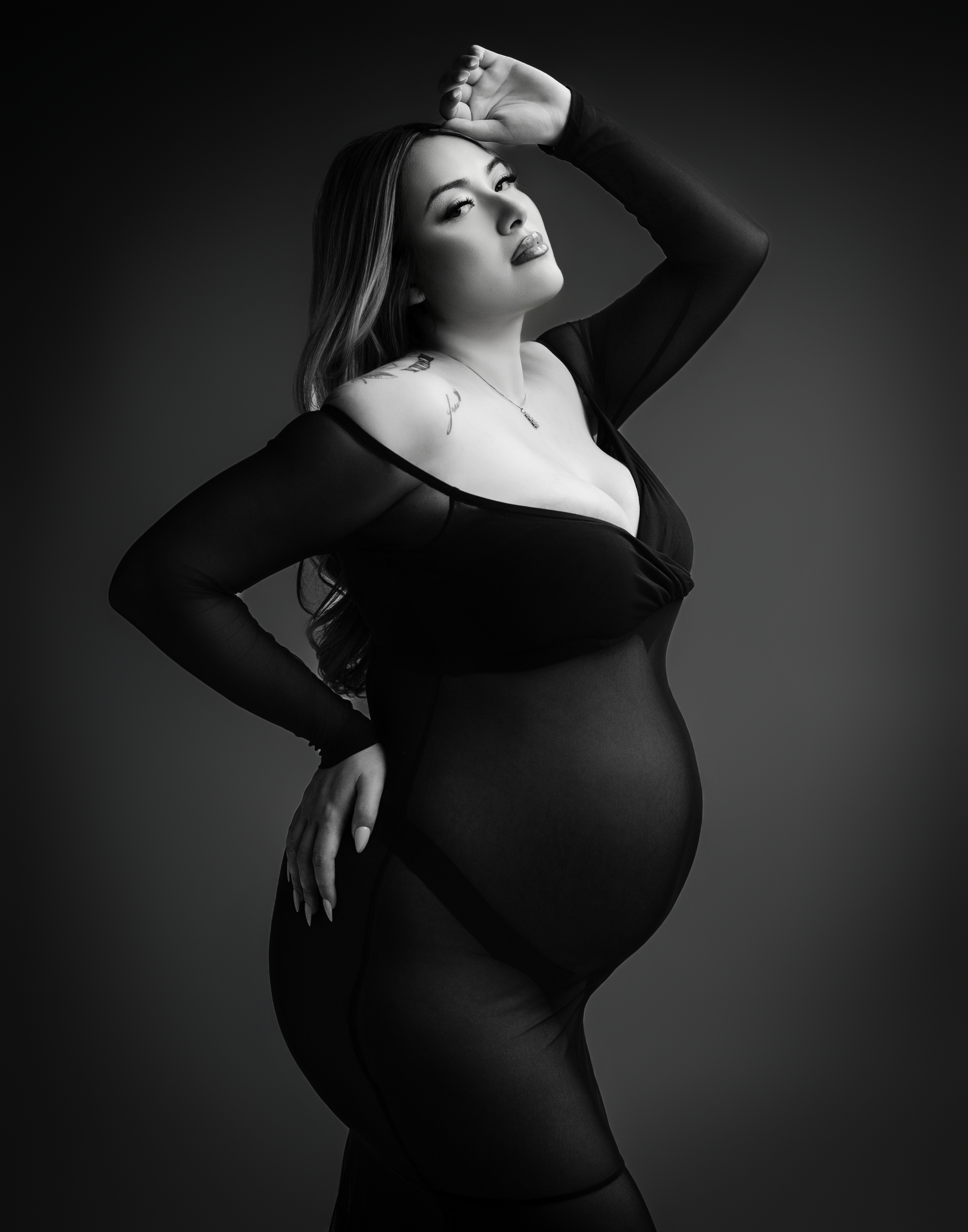Pregnant mom in black dress on backdrop for maternity shoot Atlanta