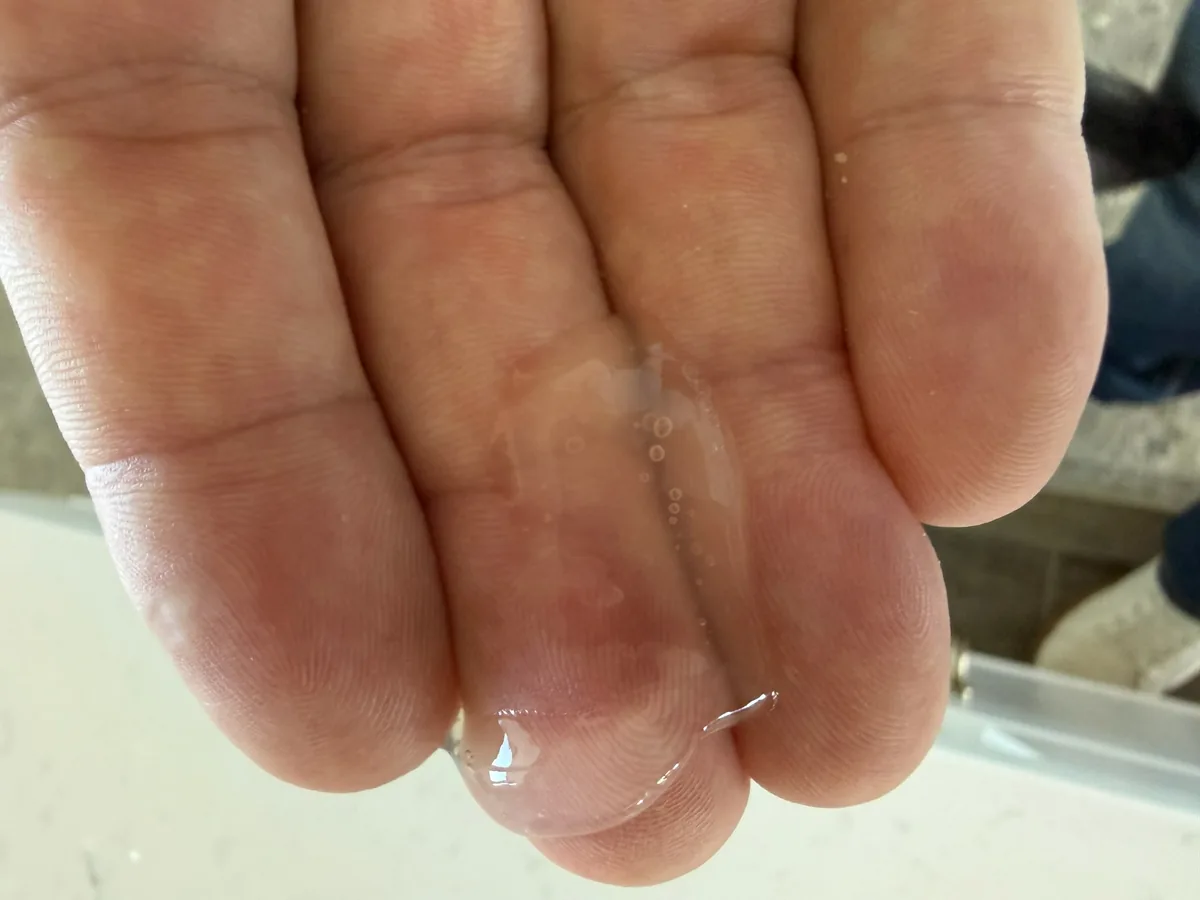 One pump of clear LactiGo carnosine gel on a fingertip, showing its light texture