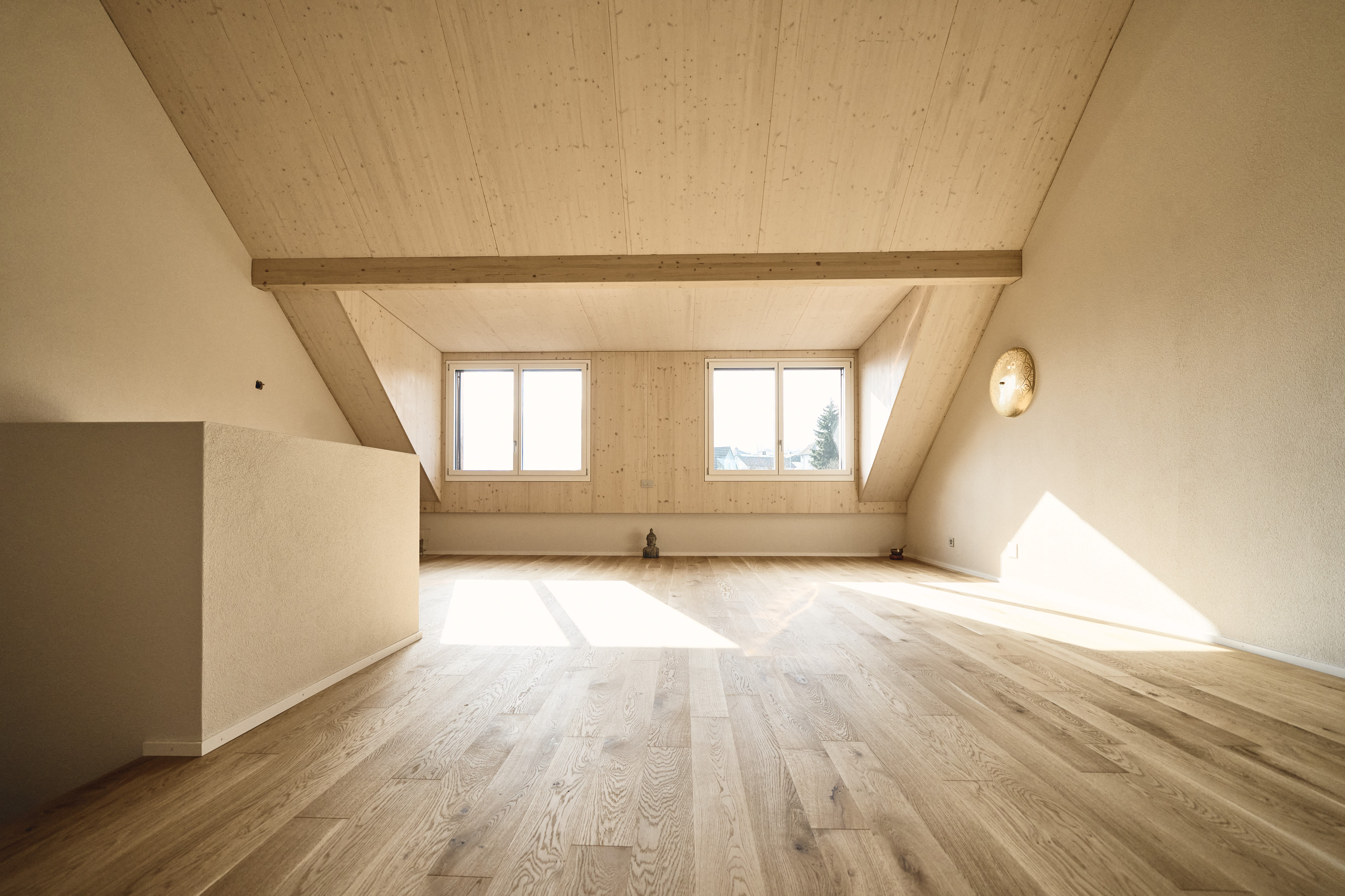 Lichtdurchfluteter Yogaraum mit Holzdecke, Parkettboden und Fensterblick für die Präsenzkurse