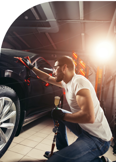 A man using a cloth to wipe and polish a black car's surface