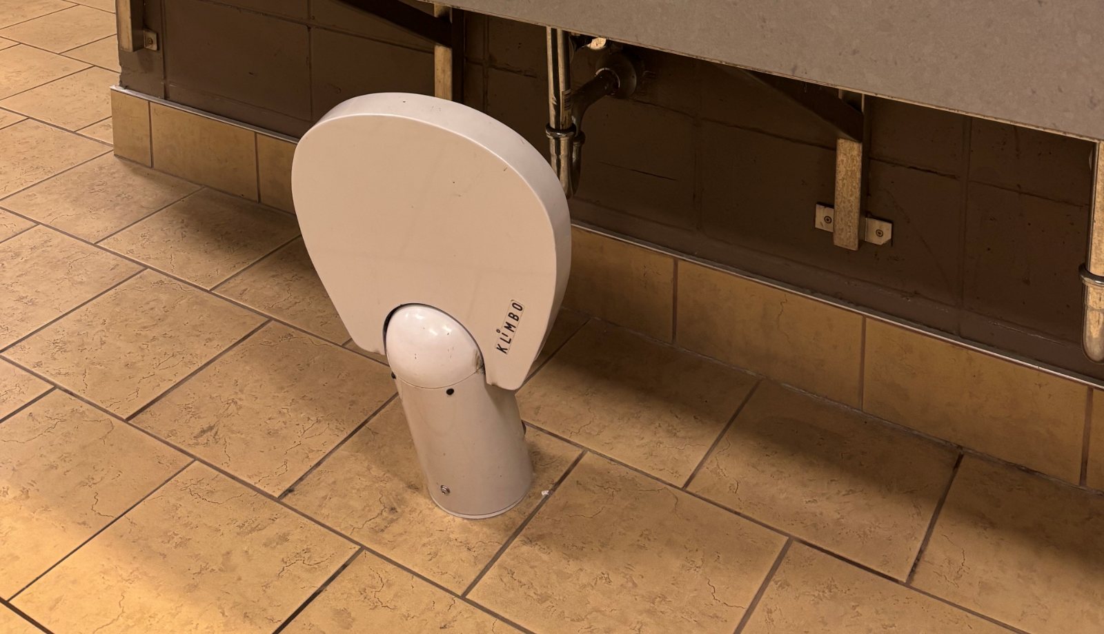 A Klimbo K01 in the retracted position under a restroom counter