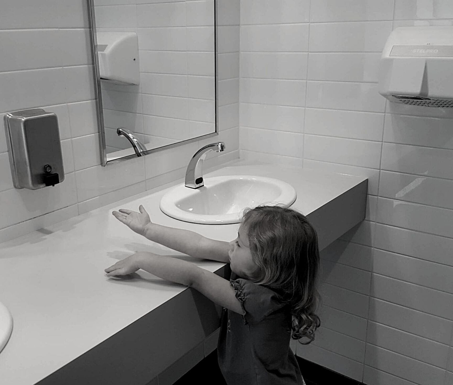 kid that cannot wash her hands because sink is too high and unaccessible