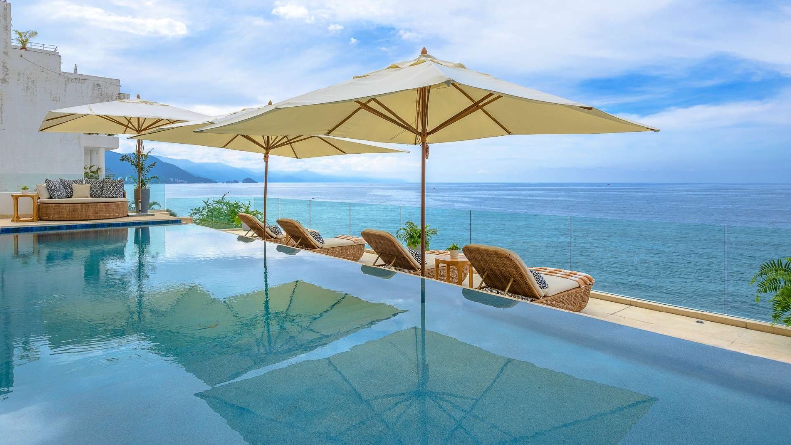 Daytime infinity pool with wicker loungers and mountain panorama
