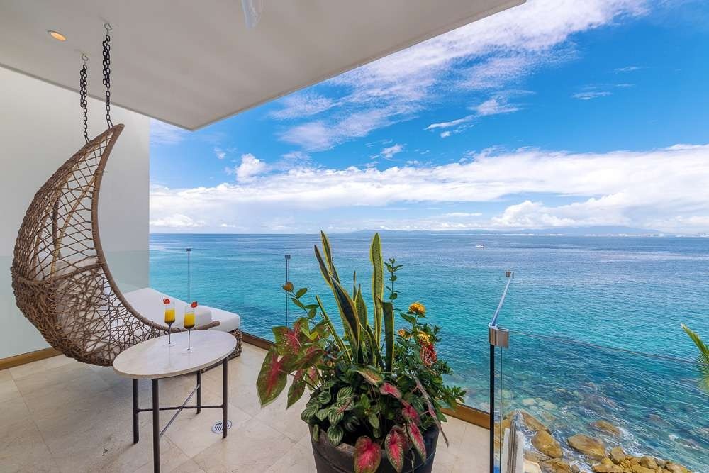 Private balcony with hanging chair over crystal turquoise ocean