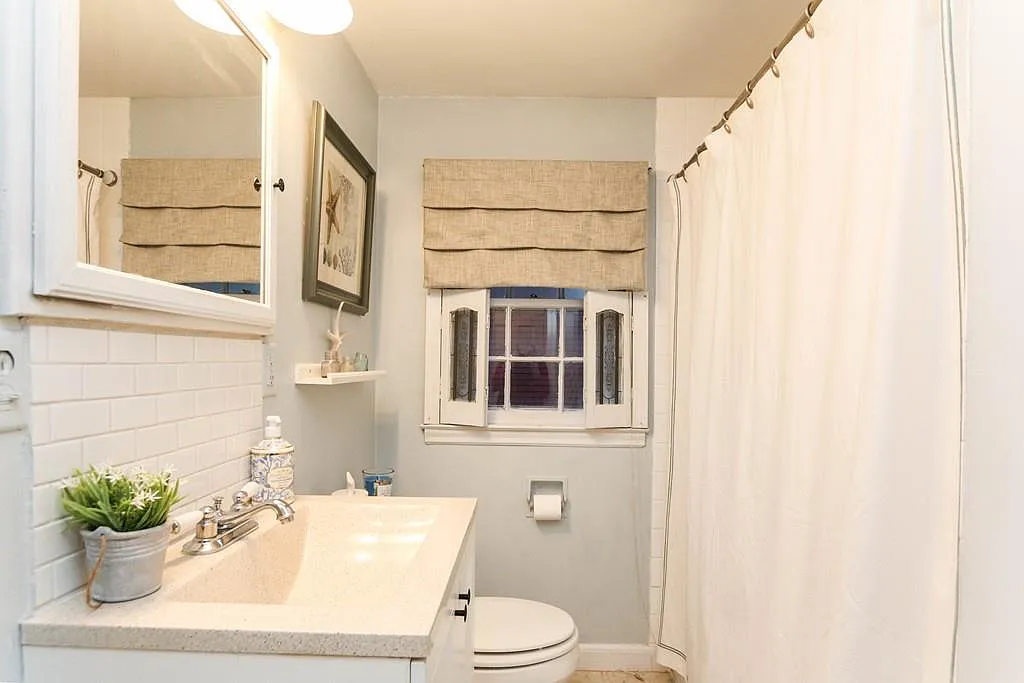 Bathroom before — builder-grade tile, burlap curtains