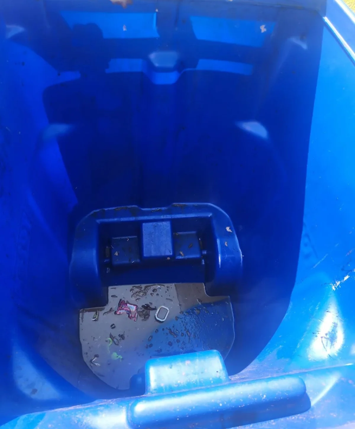 Close-up of the interior of a dirty, light blue plastic cooler with prominent rust-colored stains and debris.