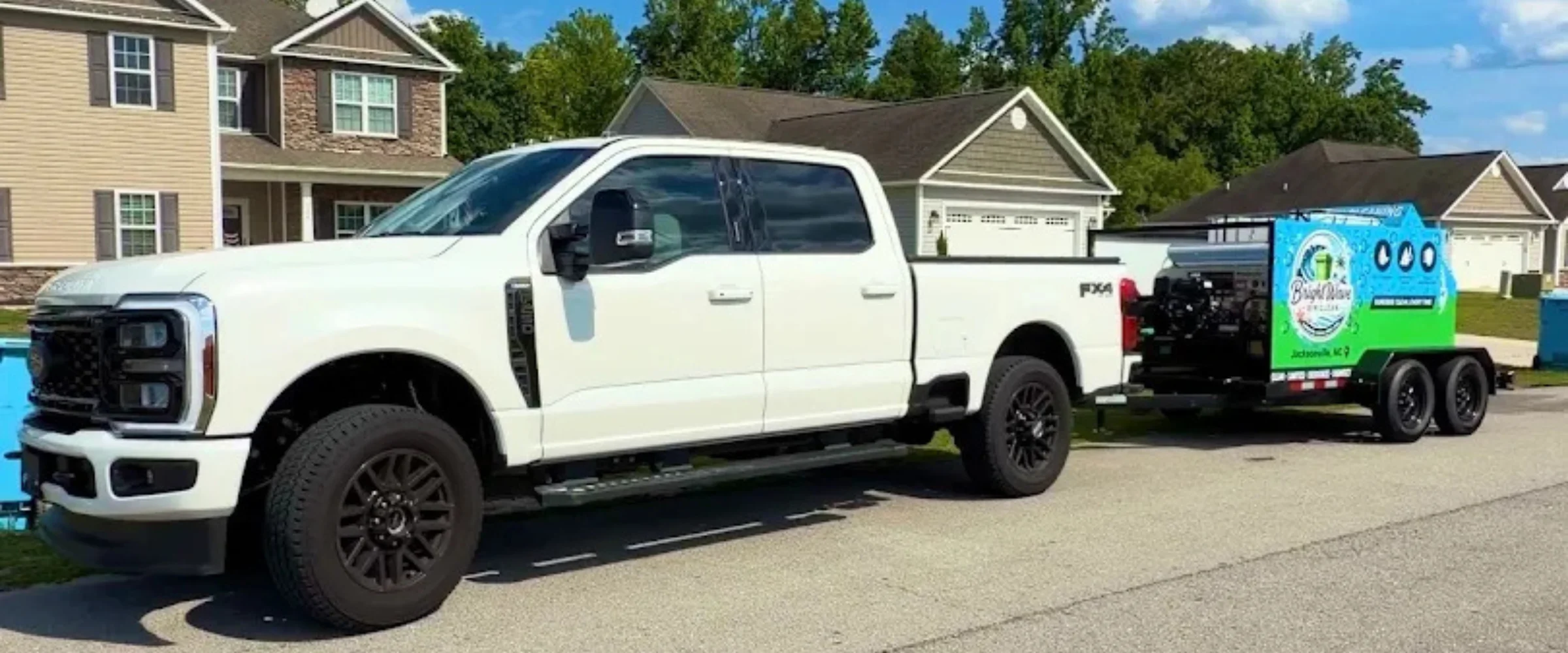 A white Ford F-Series pickup truck towing a Bright Wave Power Wash trailer on a residential street.