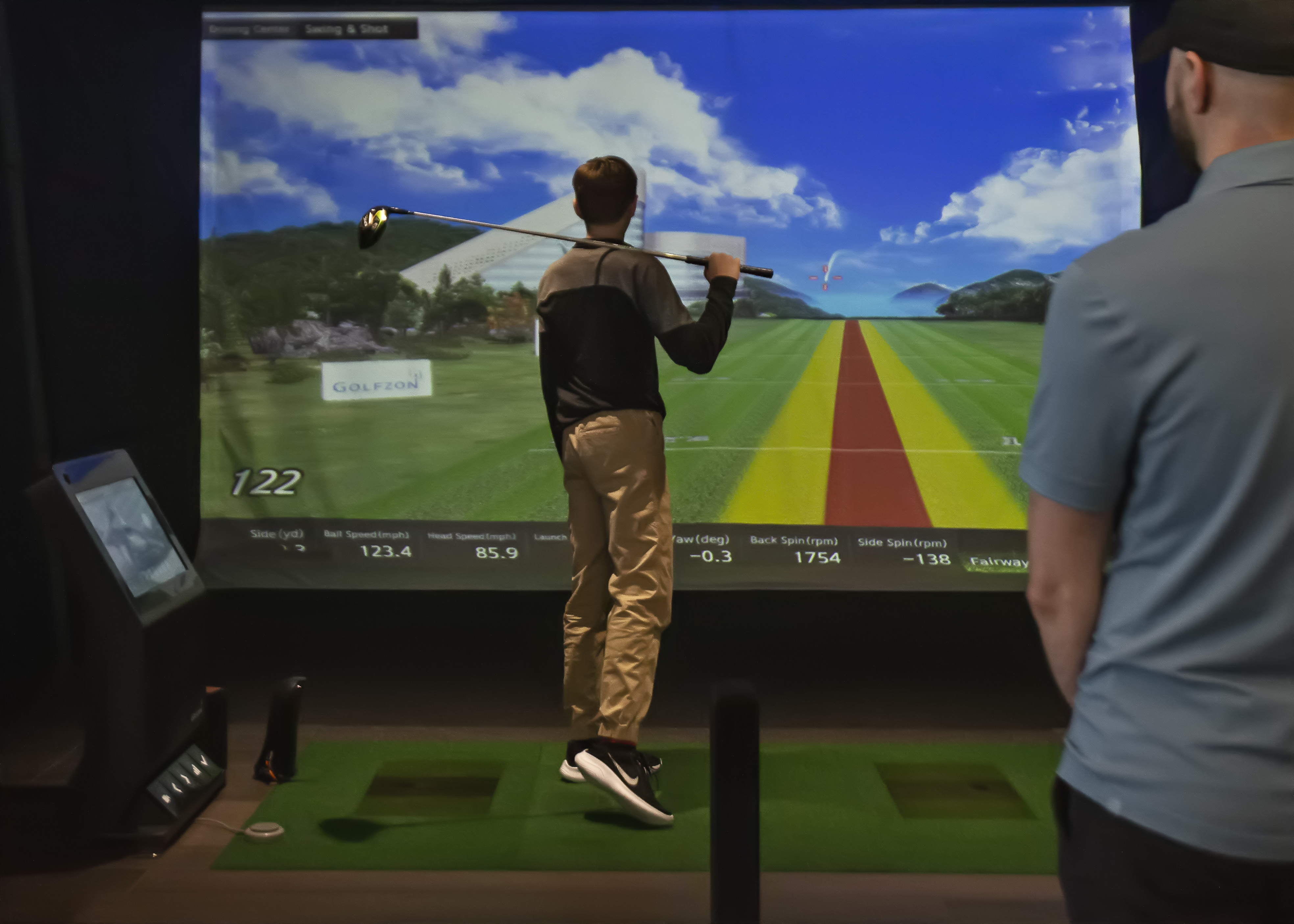 Teen boy swinging at Golfzon simulator Caddie Kids Golf Camp Ages 13-17 Avid Caddie