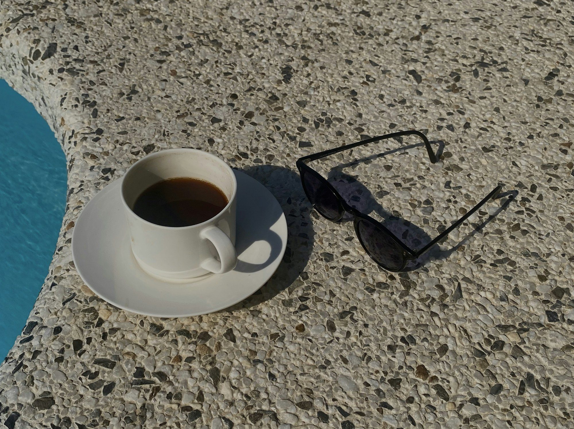Coffee and sunglasses on a sunny pool deck