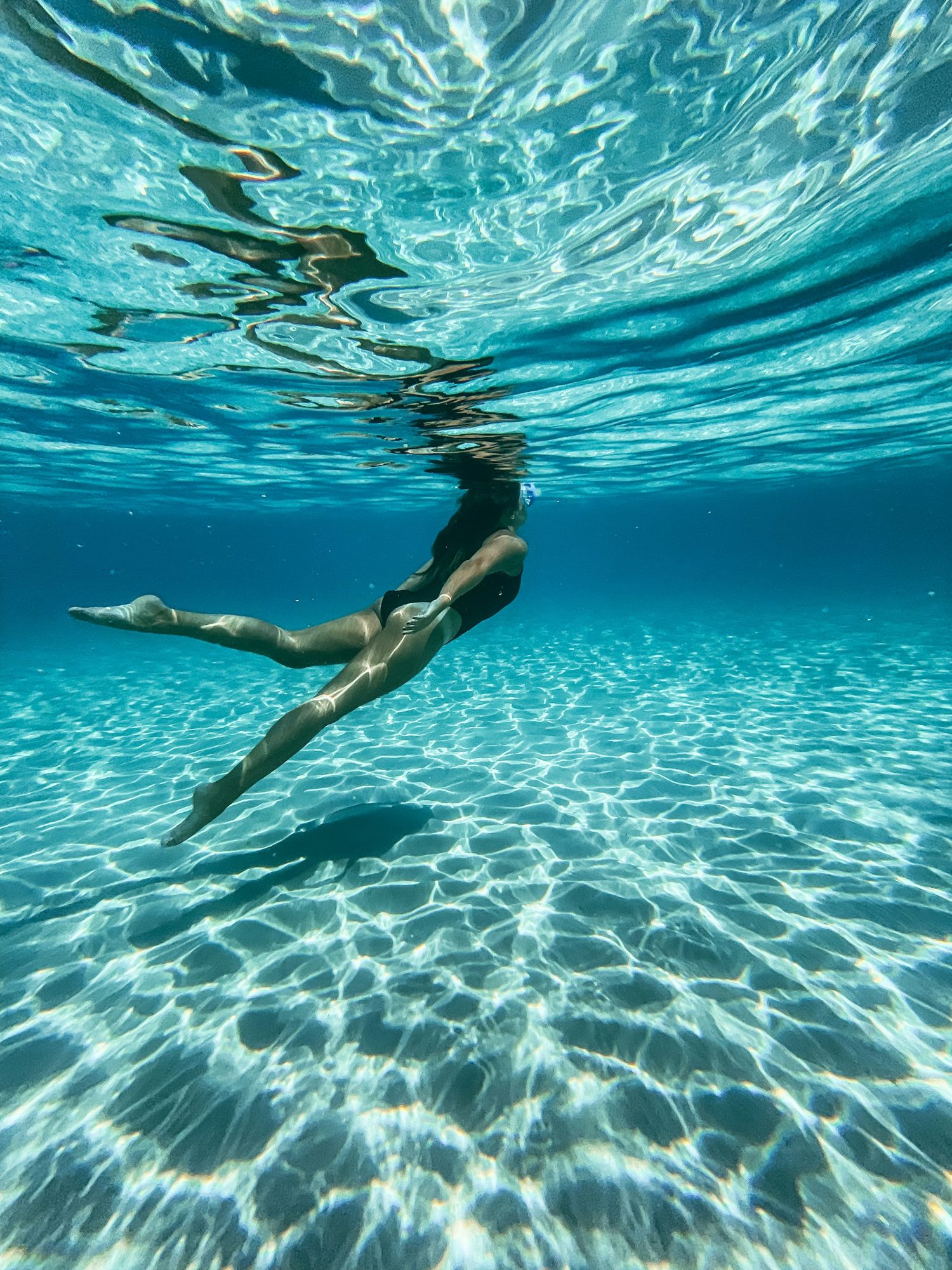 A swimmer gliding underwater through clear blue water