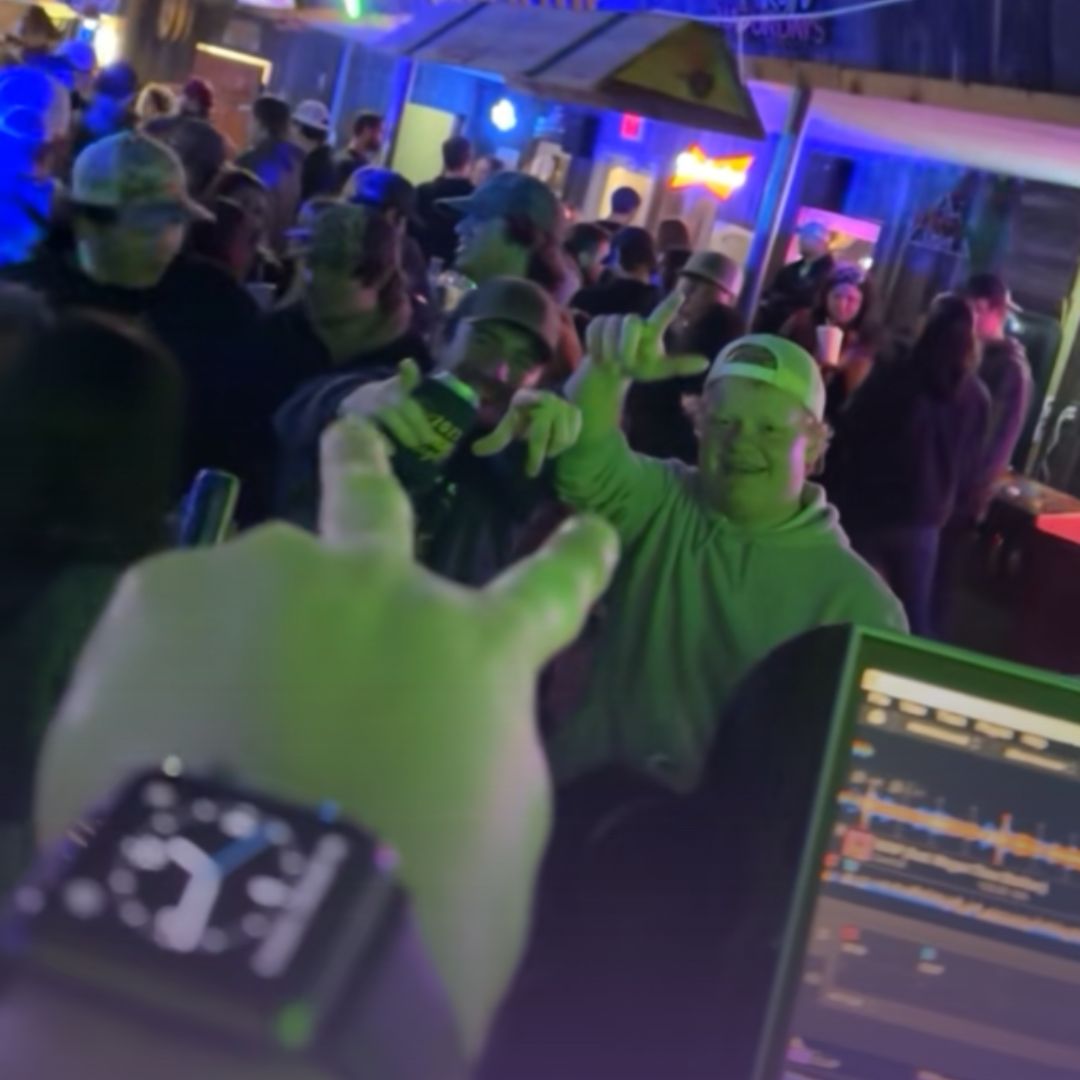 DJ performing at packed bar with crowd dancing to professional sound system
