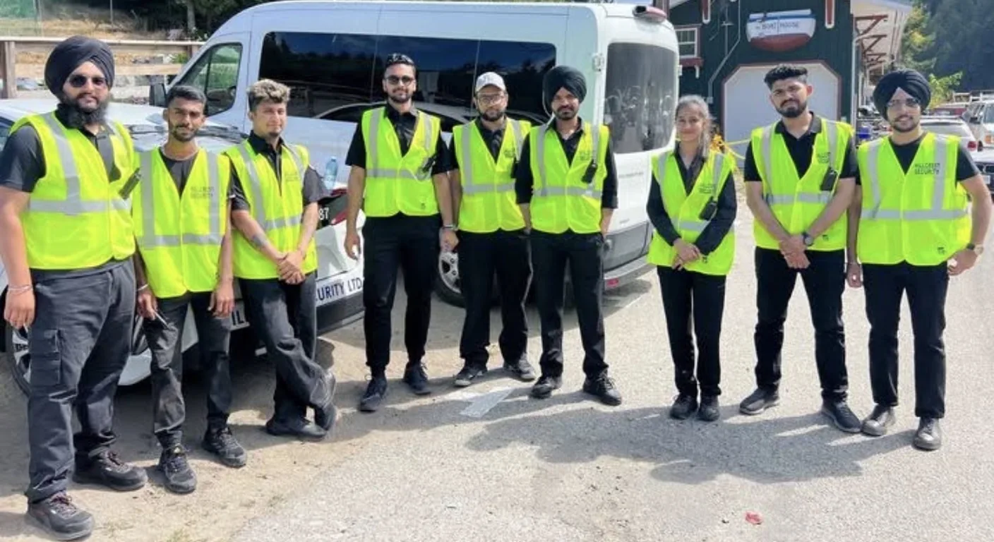 Team of Hillcrest Security guards in high-visibility vests beside a company van and car