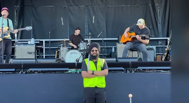 Hillcrest Security guard in a high-visibility vest standing in front of a concert stage while a band plays