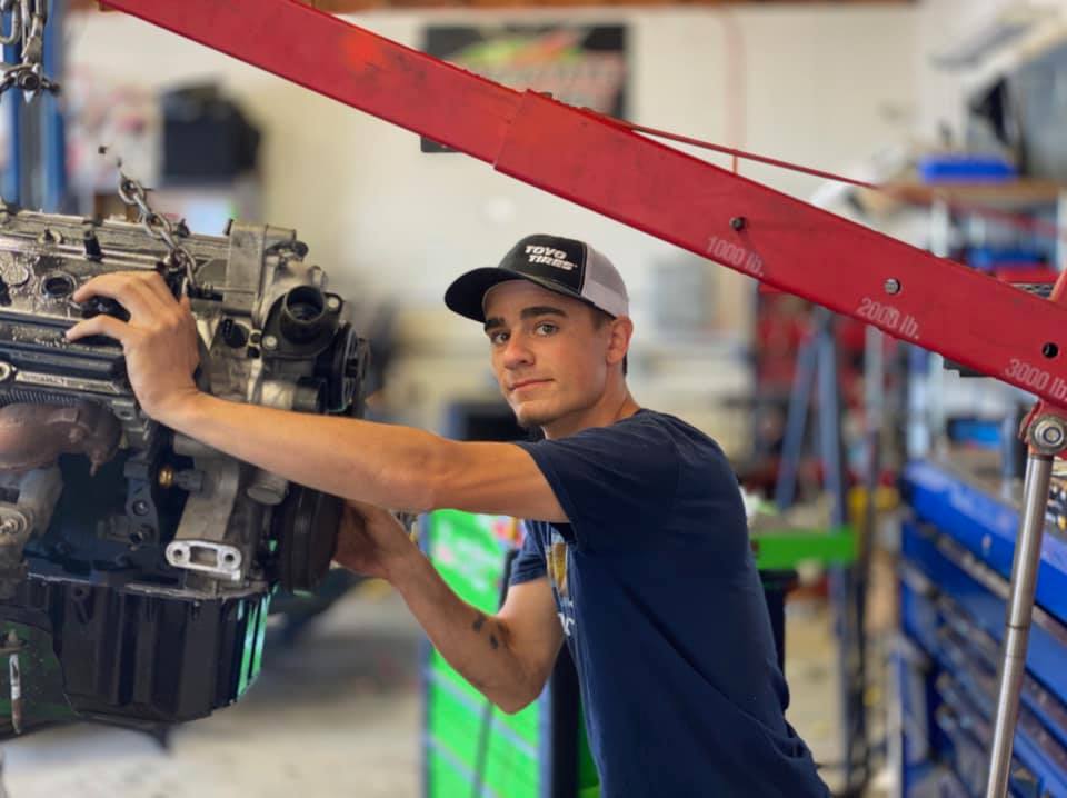 Technician performing engine removal on cherry picker hoist at Sager & Sons Auto in Boise, ID