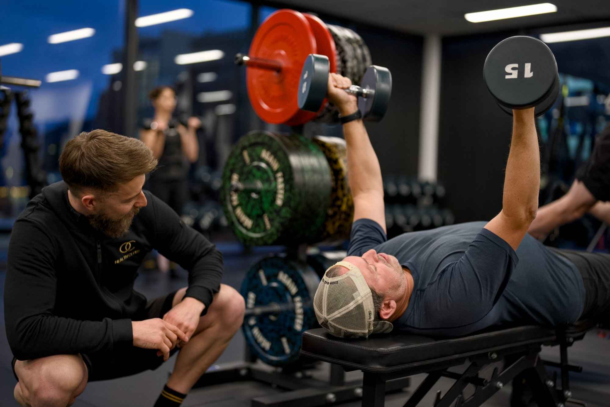 Personal trainer spotting a member during a dumbbell shoulder press at OC Health Clubs, Queenstown