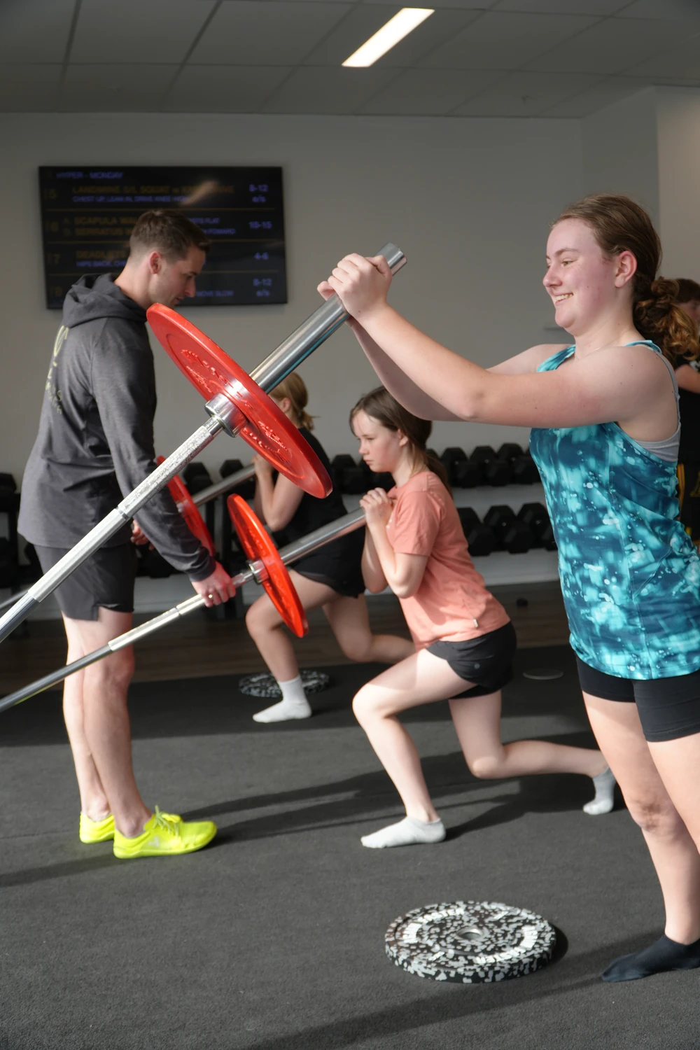 A coach guiding teenagers during a BUILD strength-training session at OC Health Clubs.